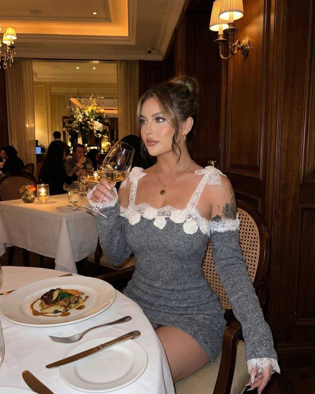 Celestine Mini Dress by Lauven, bodycon silhouette with lace trim, worn at an elegant dinner setting.