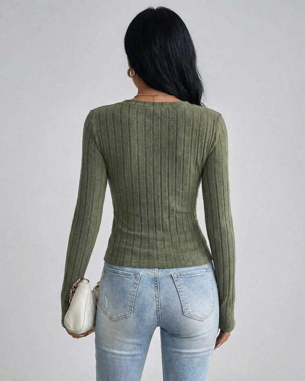 Back view of a woman wearing the Sahara Sweater by Lauven, showcasing its ribbed knit design in green.