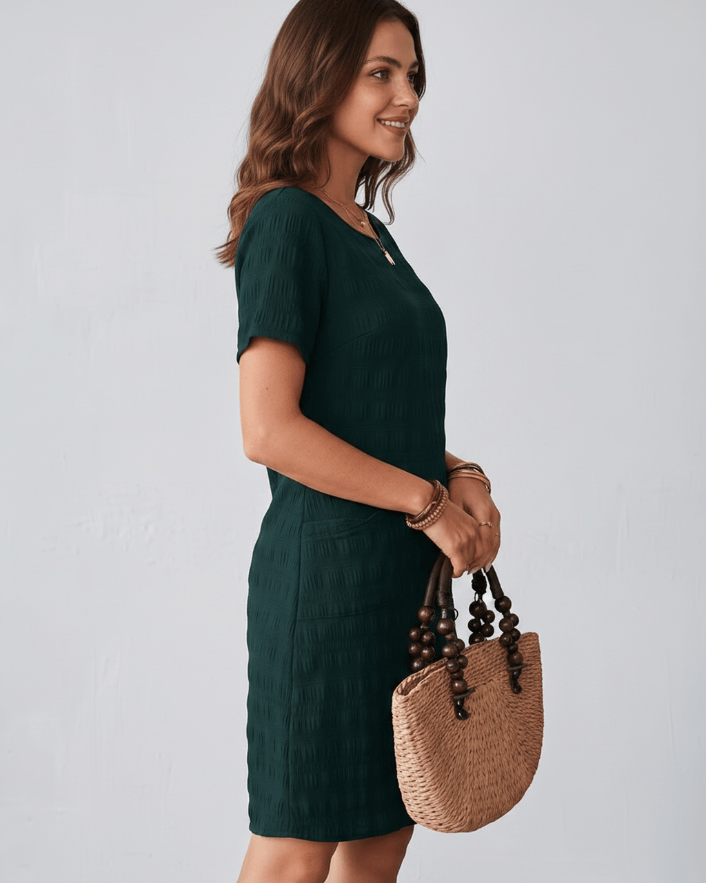 Avelin Mini Dress in textured fabric with round neckline, short sleeves, styled with a straw bag. Lauven brand.