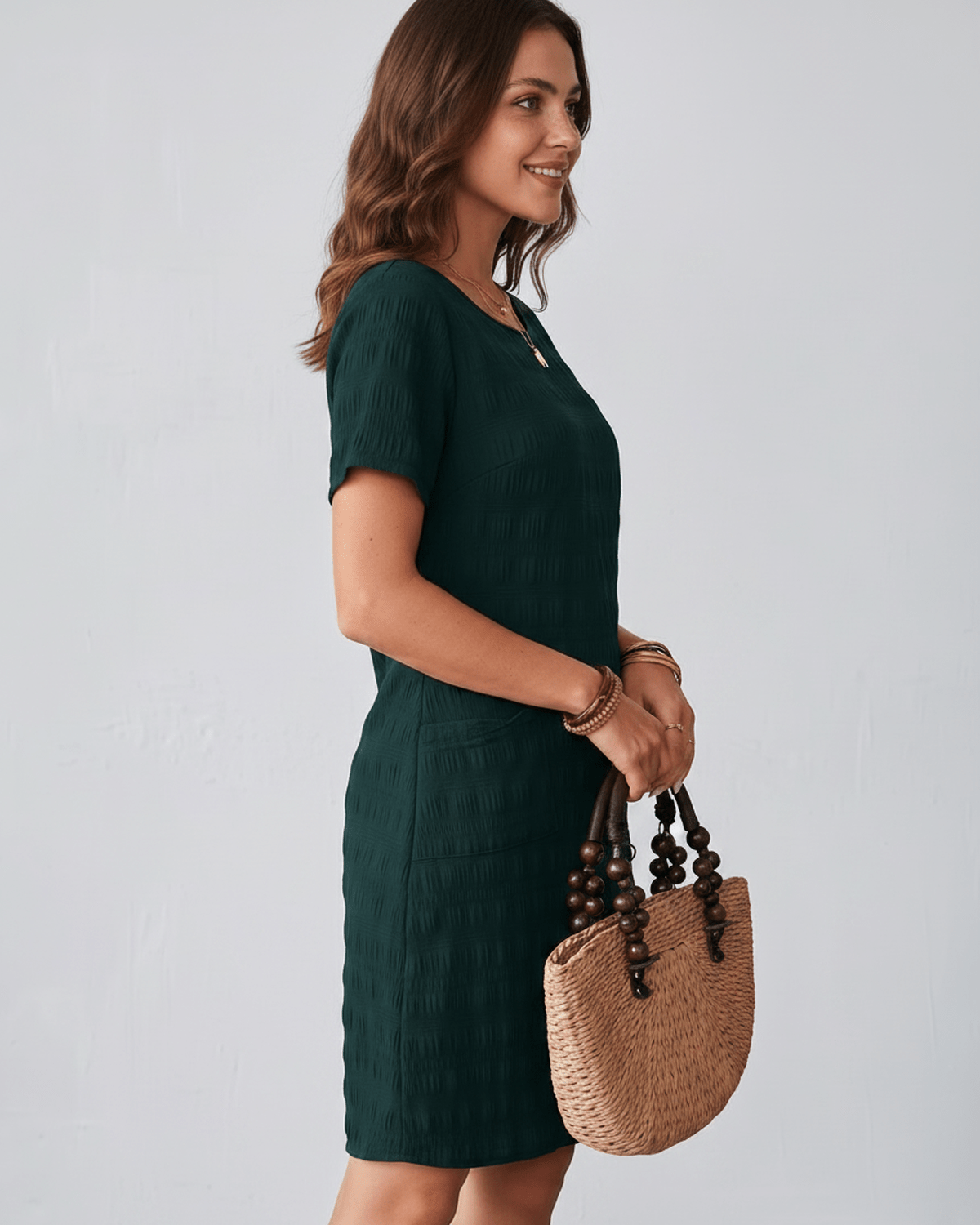 Avelin Mini Dress in textured fabric with round neckline, short sleeves, styled with a straw bag. Lauven brand.