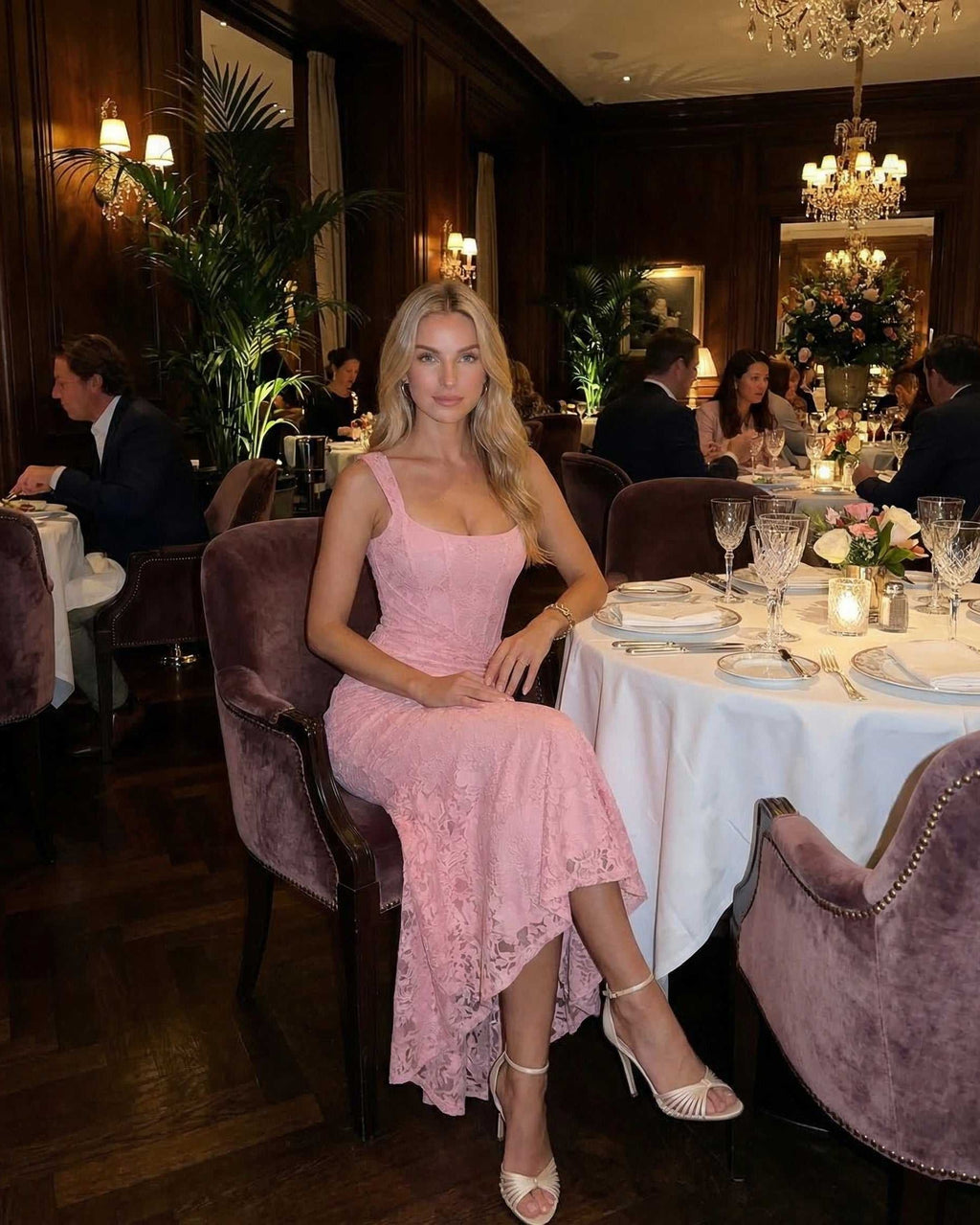 Model wearing Blush Maxi Dress by Lauven in soft pink, sitting elegantly at a dining table.