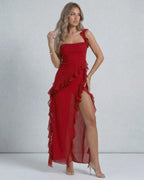 Lauven Carmine Maxi Dress features sheer red fabric, ruffled shoulder straps, and a stylish asymmetric hemline.