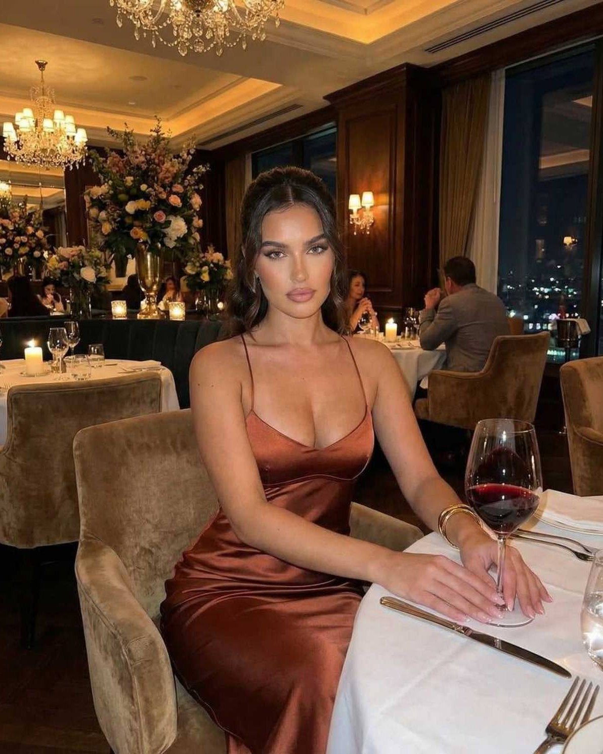 Celeste Maxi Dress by Lauven, elegant satin V-neck evening gown in rich copper worn at a dining table.