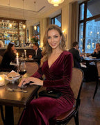 Celeste Maxi Dress in luxurious burgundy velvet by Lauven, worn at an elegant dinner setting.