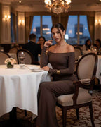 Lauven Celeste Maxi Dress in chocolate brown, elegant off-shoulder fishtail silhouette worn at a dining table.