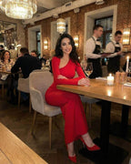 Celeste Maxi Dress worn by a woman in a restaurant, showcasing the elegant red sheath with diagonal collar from Lauven.