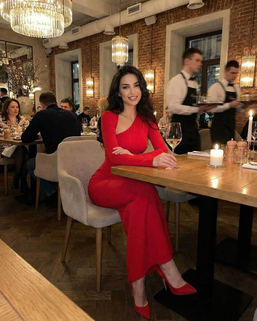 Celeste Maxi Dress worn by a woman in a restaurant, showcasing the elegant red sheath with diagonal collar from Lauven.