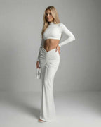Celeste Maxi Dress by Lauven showcasing a sleek white ankle-length design with ruched detailing and long sleeves.