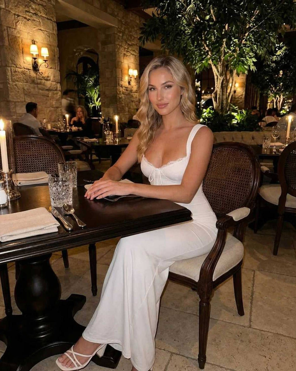 Celeste Maxi Dress by Lauven, elegant white satin silhouette at a dinner table in a stylish restaurant setting.