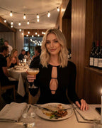 Woman enjoying dinner in a restaurant wearing the Celeste Midi Dress by Lauven, featuring hollow out detail.