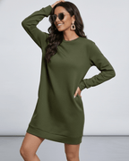 Model wearing the Celeste Mini Dress by Lauven, a casual olive green sweatshirt dress with pockets.