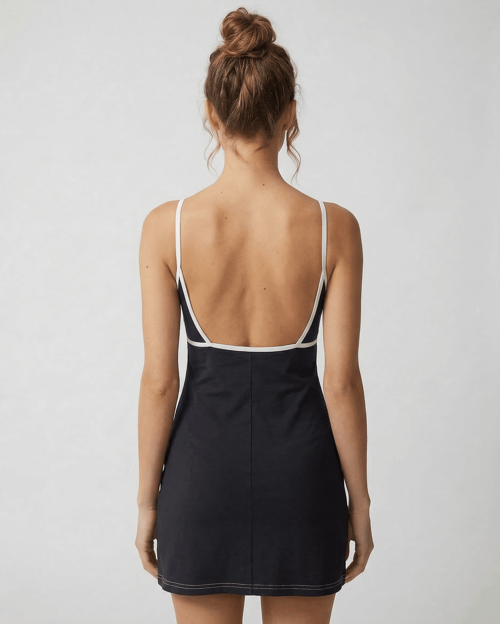 Back view of a model wearing the Celeste Mini Dress by Lauven, showcasing its sleek cut-out detail and flattering fit.