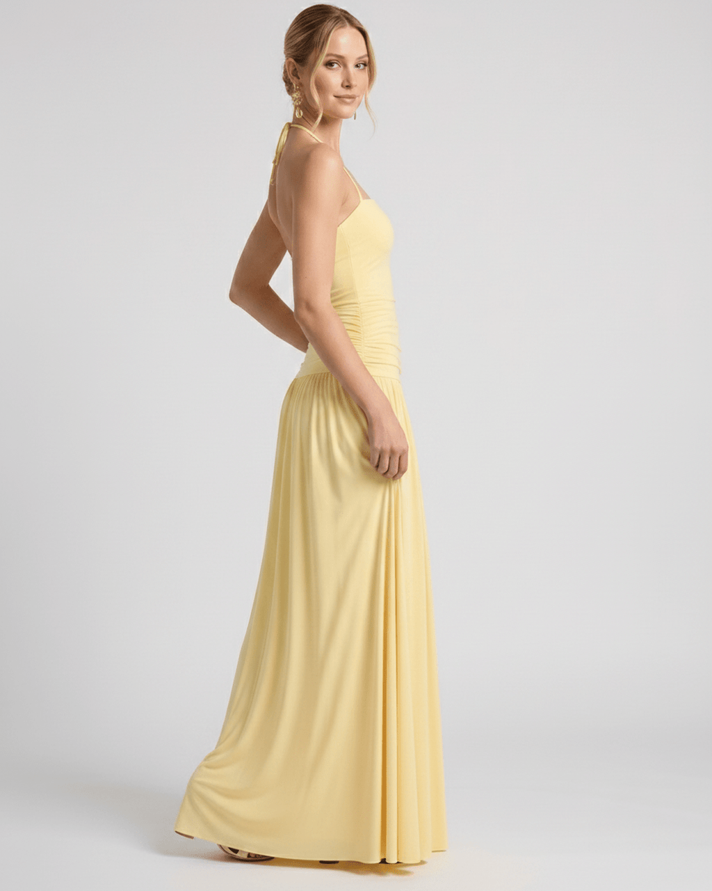 Elara Maxi Dress in soft yellow stretch jersey, featuring a halter neck and gently ruched waist for an elegant silhouette by Lauven.