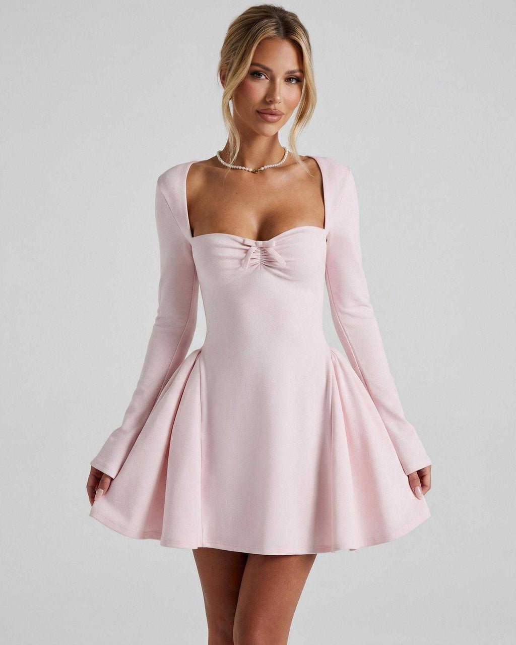 Elvire Mini Dress in light pink, featuring long sleeves, fit-and-flare silhouette, and bow detail by Lauven.