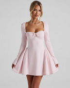 Elvire Mini Dress in light pink, featuring long sleeves, fit-and-flare silhouette, and bow detail by Lauven.
