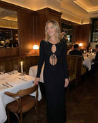 Elysian Maxi Dress by Lauven, sleek black cotton blend with hollow-out details, worn in an elegant dining setting.