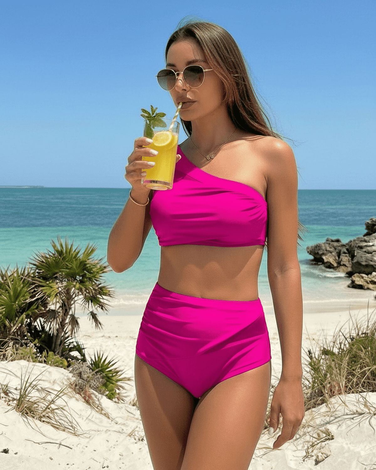 Fuchsia Two-Piece Swimsuit by Lauven, featuring a modern asymmetric design and enjoying a drink on the beach.