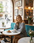 Woman in Glacier Mini Dress by Lauven sitting at a café table with a croissant and coffee.