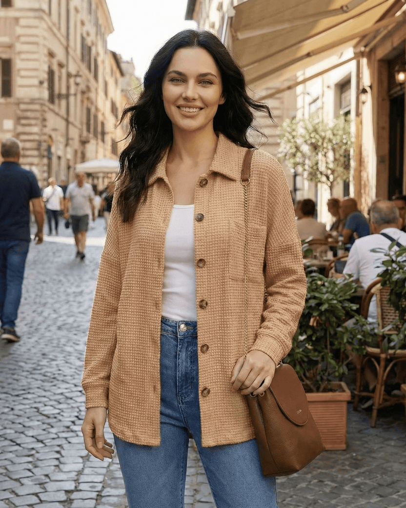 Model wearing Sienna Jacket by Lauven, a beige waffle knit longline casual fit in an outdoor cafe setting.