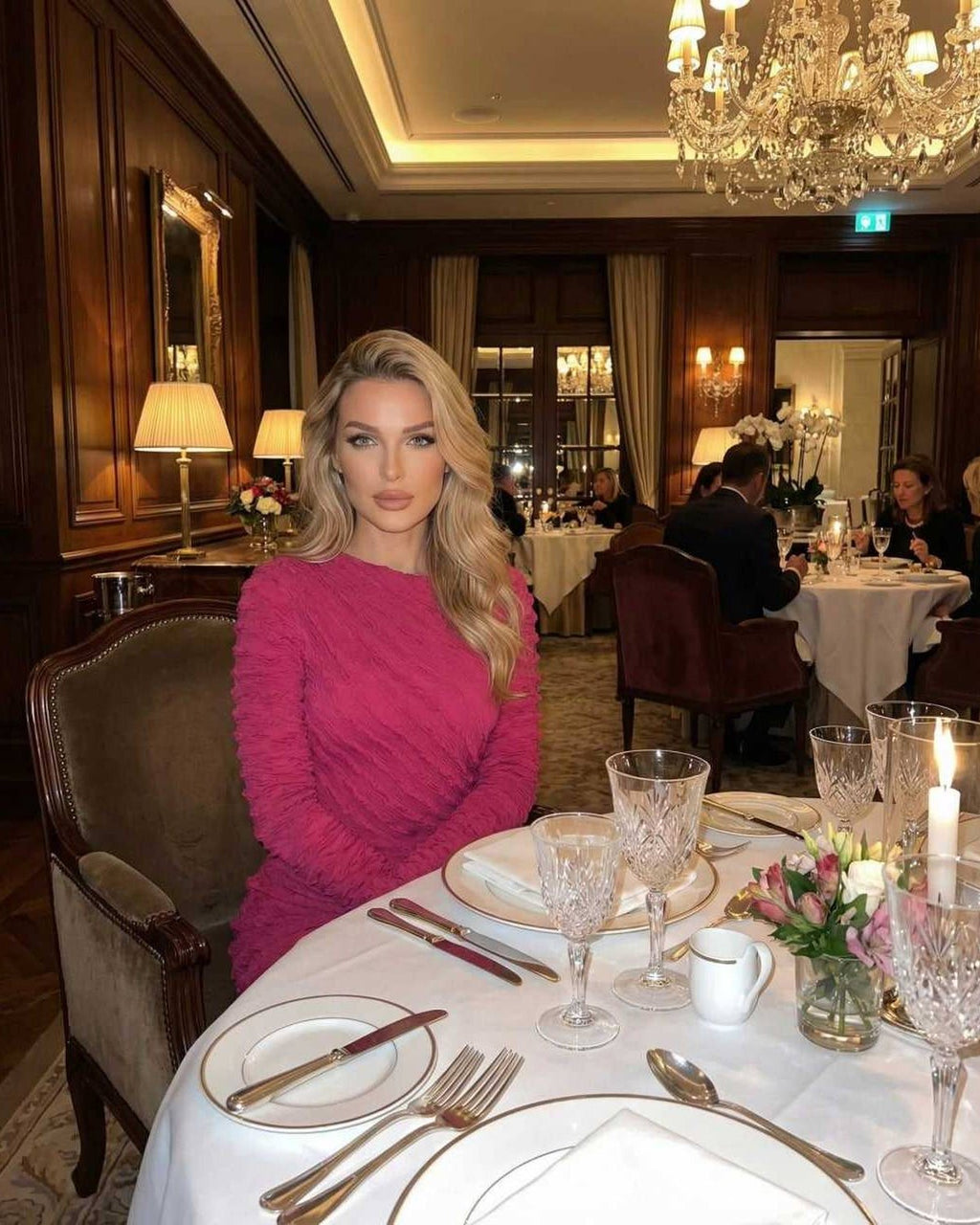 Isla Maxi Dress by Lauven, a textured pink long sleeve knitted maxi dress, elegantly worn at a dining table.