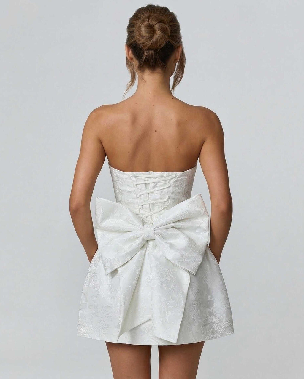 Ivory Mini Dress by Lauven featuring a strapless design and large bow detail on the back.