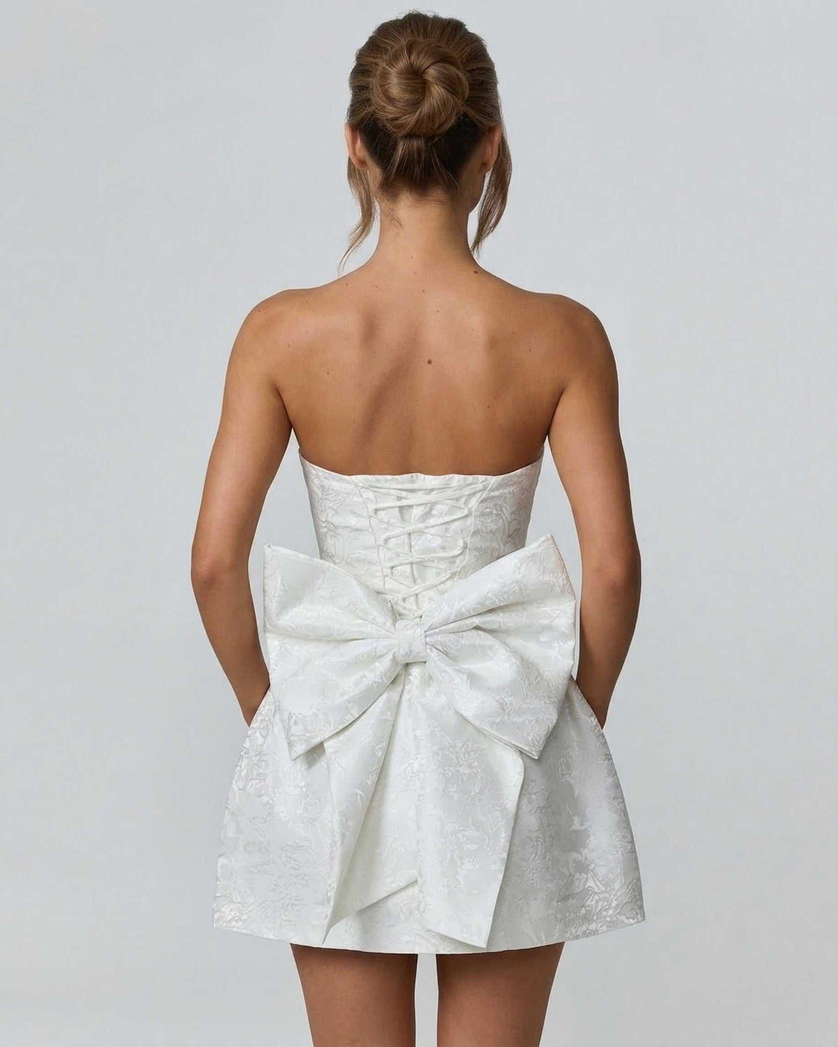 Ivory Mini Dress by Lauven featuring a strapless design and large bow detail on the back.