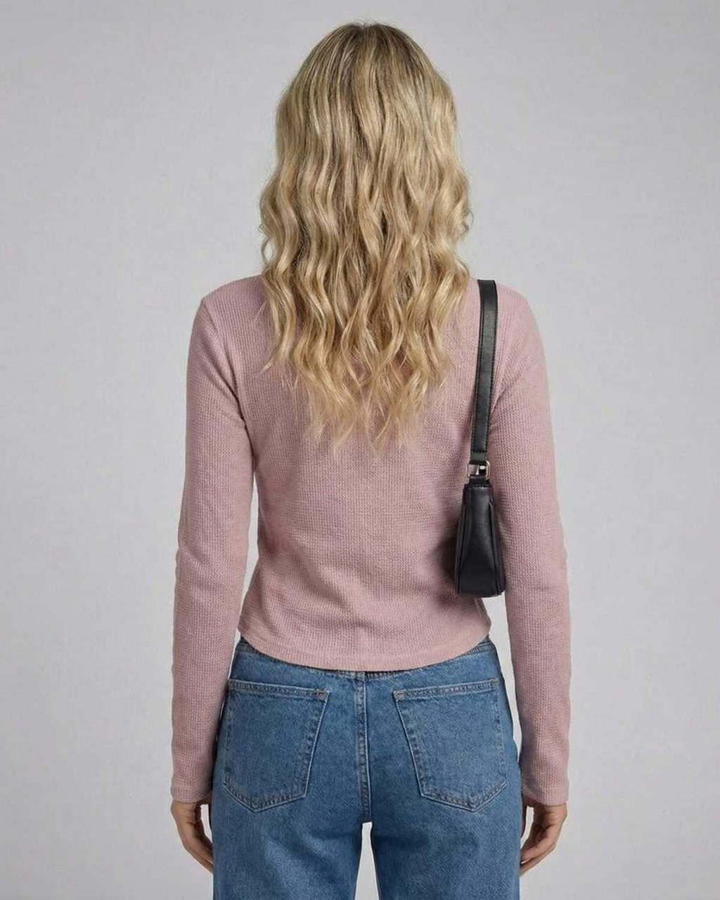 Back view of a woman wearing the Arden Long Sleeve top in dusty rose, paired with jeans and a small black bag.