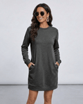 Woman in Astrid Mini Dress by Lauven, a dark charcoal sweatshirt dress with pockets and relaxed silhouette.