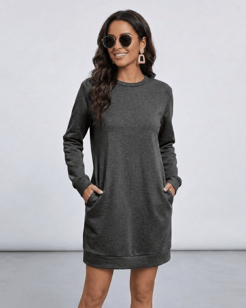 Woman in Astrid Mini Dress by Lauven, a dark charcoal sweatshirt dress with pockets and relaxed silhouette.