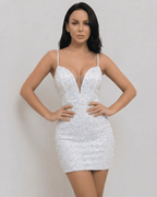 Model wearing the Aurora Mini Dress by Lauven, a white sequin V-neck mini dress with a fitted silhouette.