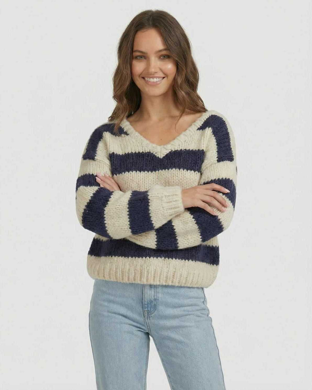 Model wearing the Capri Pullover by Lauven, a striped V-neck knit sweater in navy and ivory.