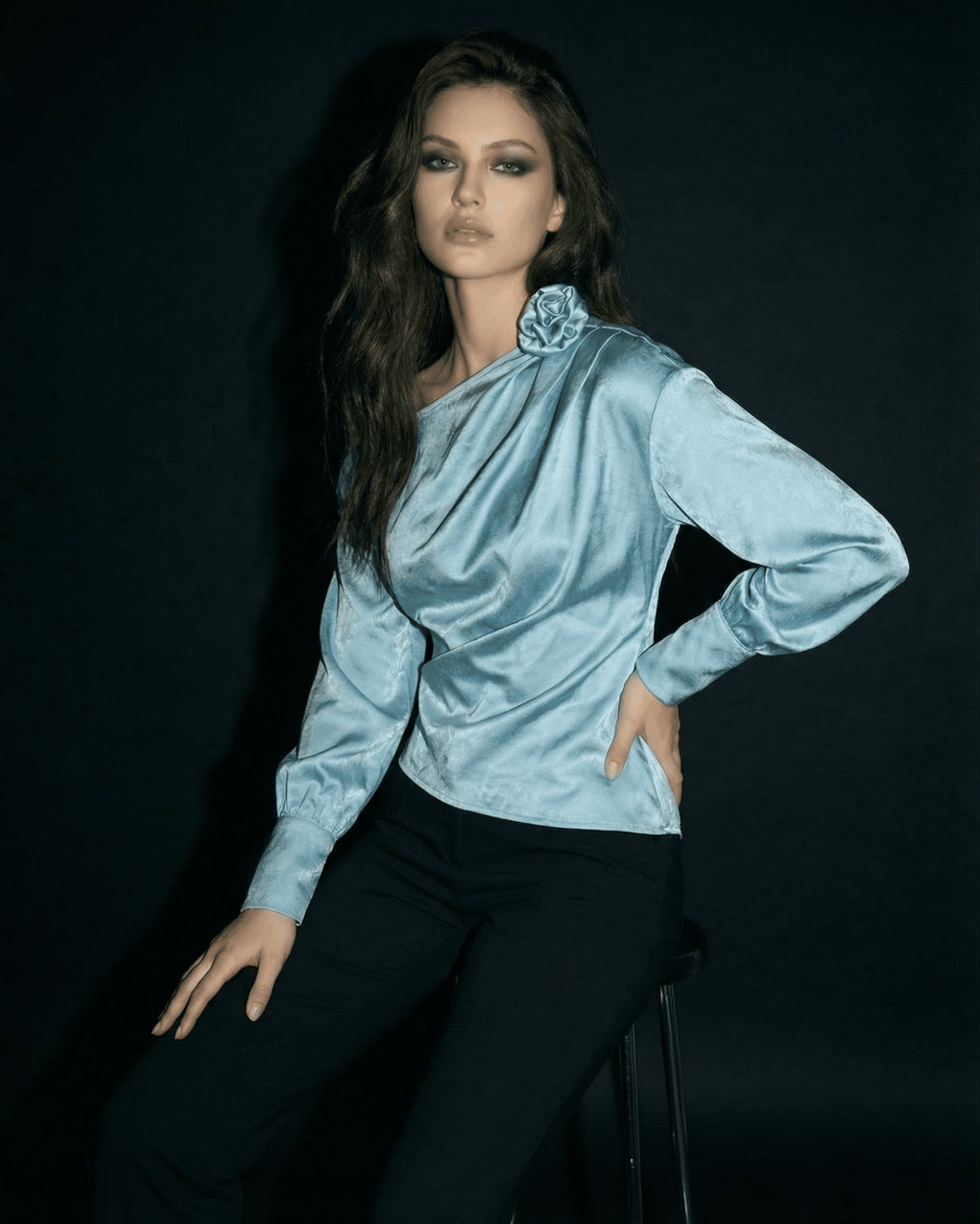 Celeste Blouse by Lauven, featuring an asymmetrical neckline and satin-style fabric, worn by model against dark background.