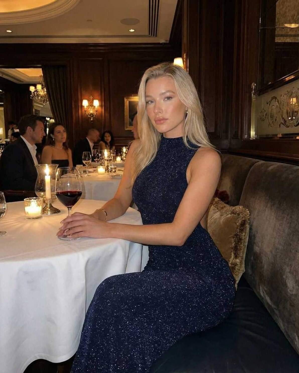 Celeste Maxi Dress by Lauven, sleek navy evening gown on a model in an elegant restaurant setting.