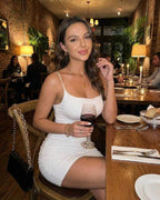 Model wearing the Celeste Mini Dress by Lauven, enjoying a drink in a cozy restaurant setting.