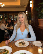 Woman wearing Celeste Mini Dress by Lauven, enjoying dinner with wine in a restaurant setting.