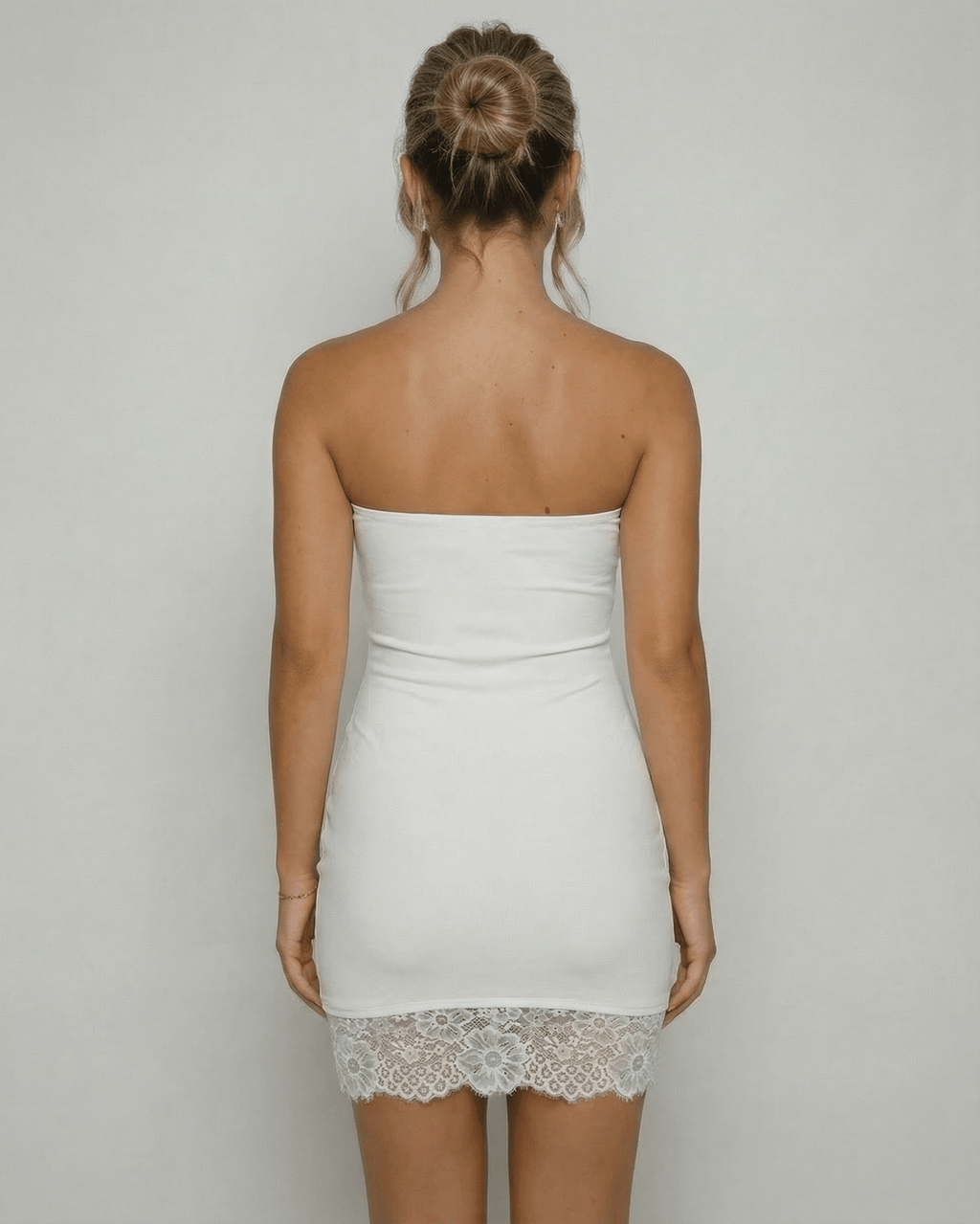Back view of a woman wearing the Lauven Celeste Mini Dress, showcasing the strapless design and lace hem detail.