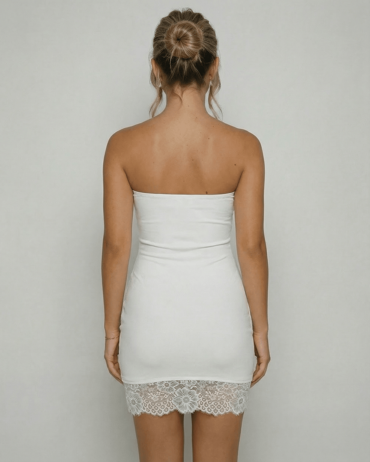 Back view of a woman wearing the Lauven Celeste Mini Dress, showcasing the strapless design and lace hem detail.