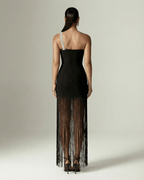 Back view of the Celestia Maxi Dress from Lauven, featuring a black one-shoulder design and elegant fringed hem.