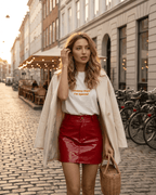Model wearing a Crimson Mini Skirt by Lauven, showcasing a high-waisted PU bodycon style with a glossy finish.