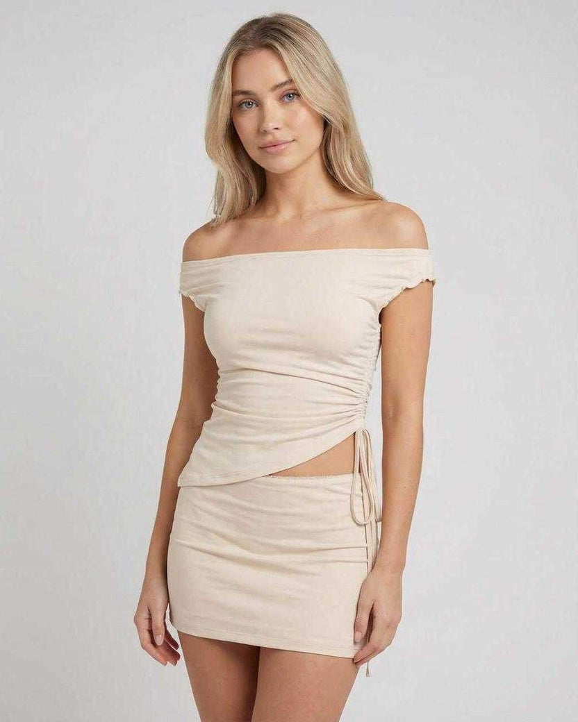 Elysia Mini Dress by Lauven featuring an asymmetric off-shoulder top and high waist mini skirt in a soft neutral tone.