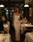 Luna Maxi Dress by Lauven featuring a sleek sheath silhouette in crisp white, styled in an elegant restaurant setting.
