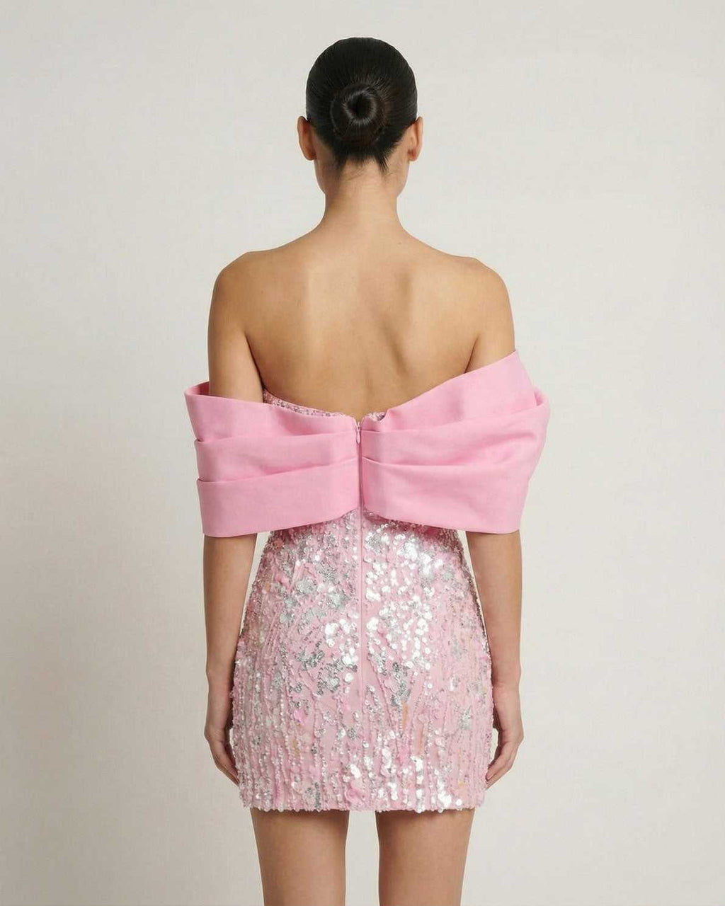 Lauven Luna Mini Dress in pink sequins, strapless with an elegant off-the-shoulder draped detail, showcasing the back view.