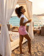 Woman in Luna Mini Skirt by Lauven, enjoying a drink by the beach during sunset, highlighting the velvet sequin design.