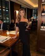 Noir Maxi Dress by Lauven in elegant off-shoulder style, worn in a chic restaurant setting.