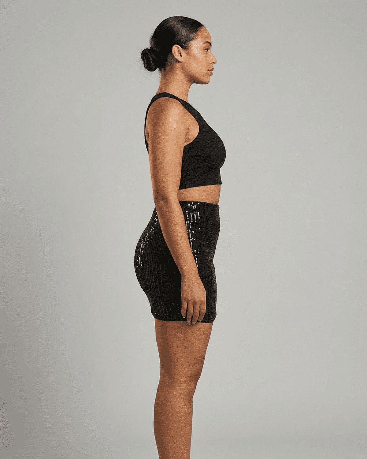 Noiré Mini Skirt by Lauven on a model showcasing the sleek sequin high waist bodycon design from the side.