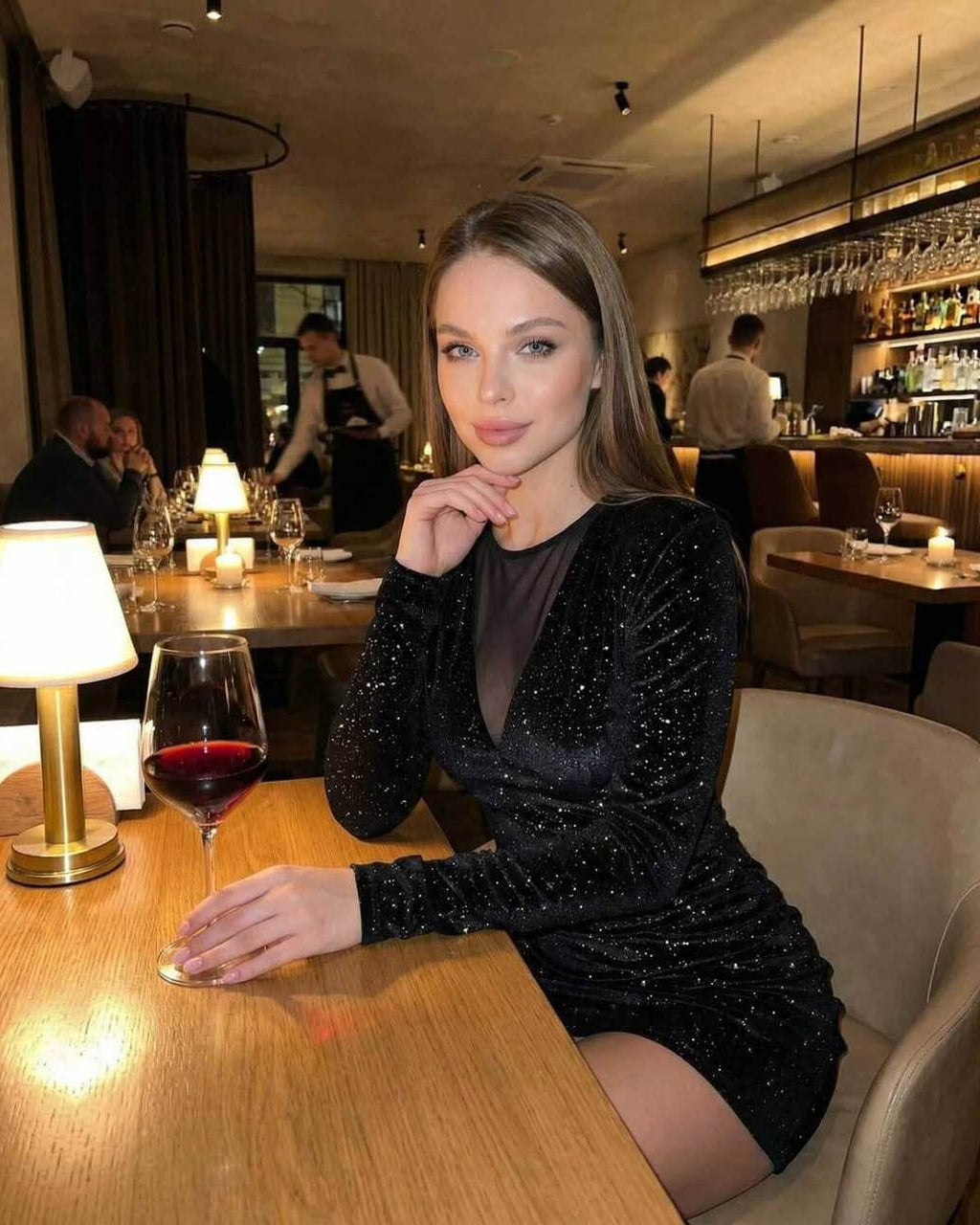 Nova Mini Dress by Lauven showcased in a chic dining setting, featuring sparkling black velvet and sheer mesh panel.