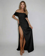 Model wearing the Nyx Maxi Dress by Lauven, featuring an off shoulder A-line silhouette and high slit.