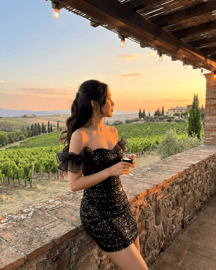 Obsidian Mini Dress by Lauven, black sequin off-the-shoulder bodycon with ruffle sleeves, sunset background.