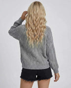 Back view of a woman wearing the grey Orion Sweater by Lauven, showcasing its cable-knit texture and long sleeves.
