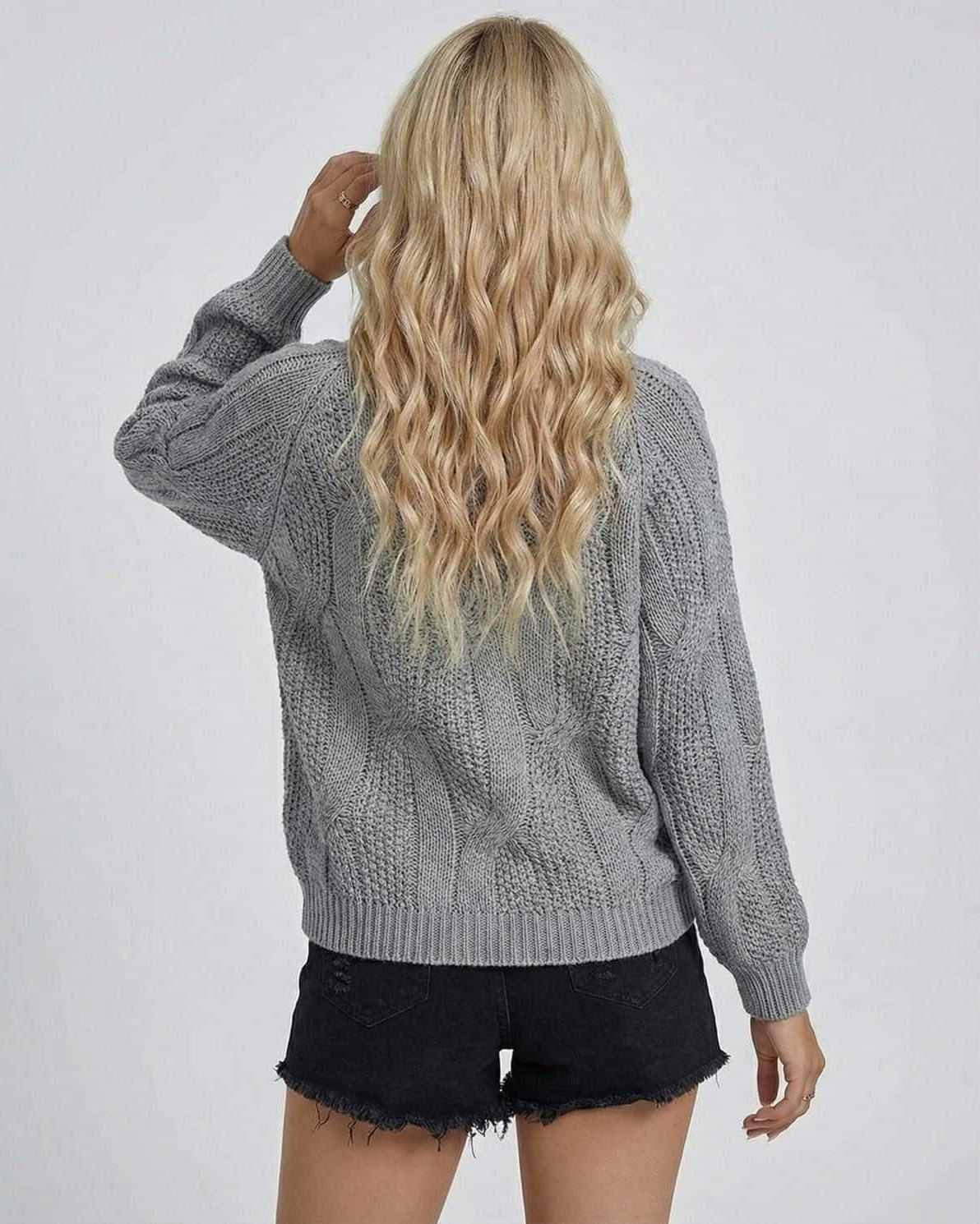 Back view of a woman wearing the grey Orion Sweater by Lauven, showcasing its cable-knit texture and long sleeves.